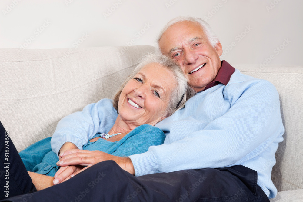 Portrait of happy elderly man with arm around spouse lying on sofa at home Portrait of happy elderly man with arm around spouse lying on sofa at home