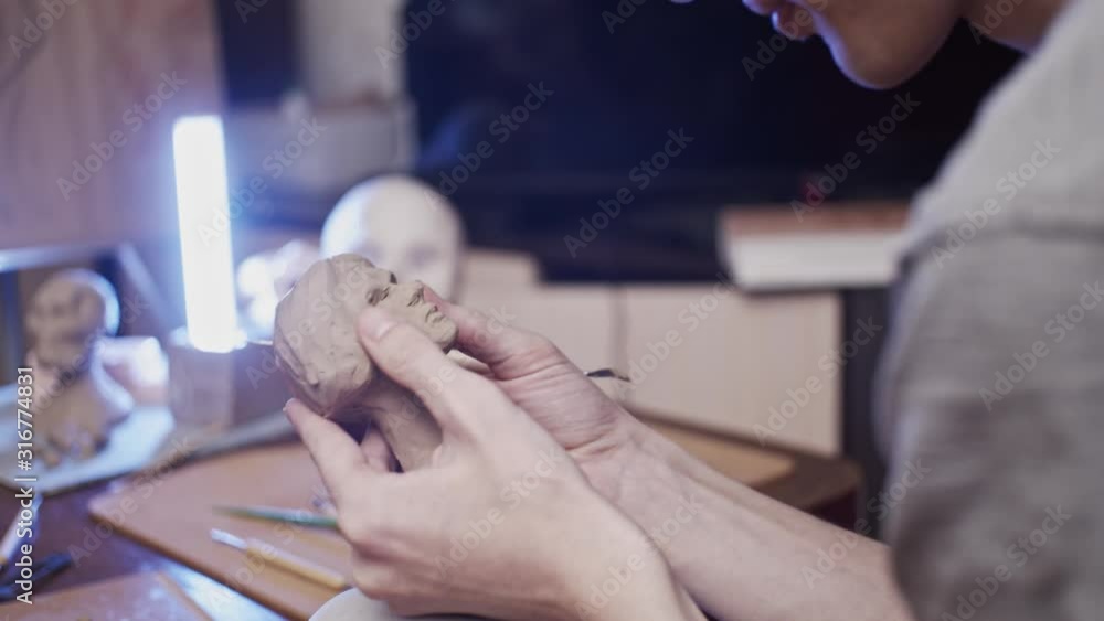 Young artist sculpting bust of woman with Plasticine (non-drying clay)