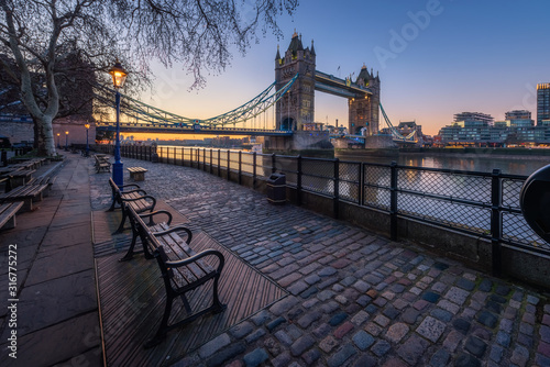 Tower Bridge with bench and street lamp foreground during sunrise  London  UK