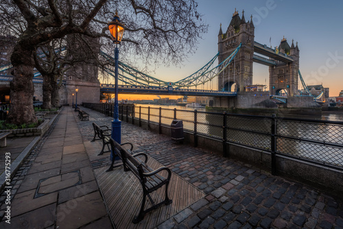 Tower Bridge with bench and street lamp foreground during sunrise  London  UK