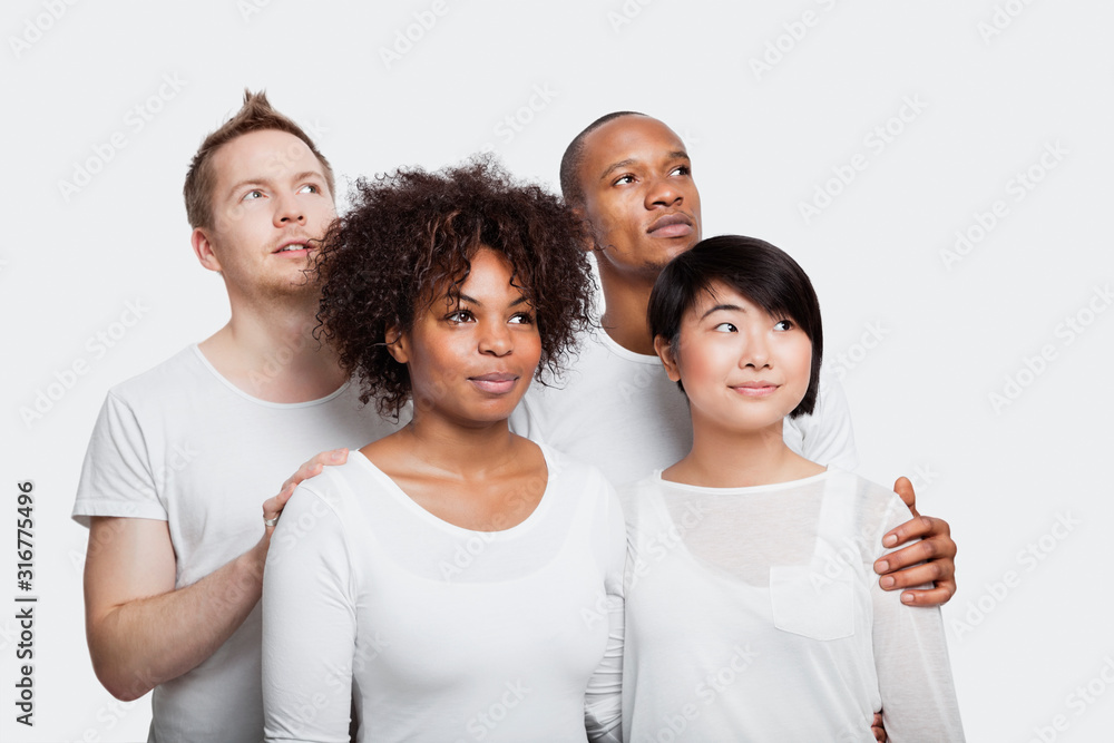 Young multi-ethnic friends in white t-shirts looking away over white background Young multi-ethnic friends in white t-shirts looking away over white background