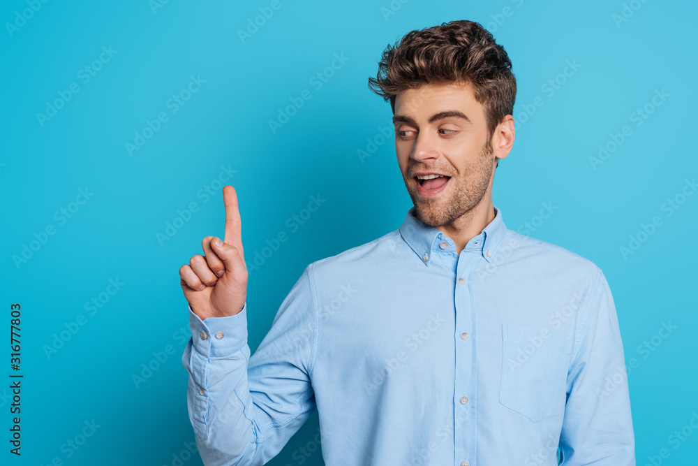positive man smiling and showing idea gesture on blue background positive man smiling and showing idea gesture on blue background