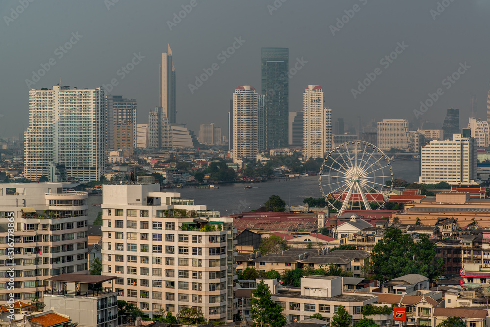 Beautiful view of Bangkok city, Skyscrapers with Asiatique Ferris Wheel along Chaopraya river in the evening, making the city modern style.