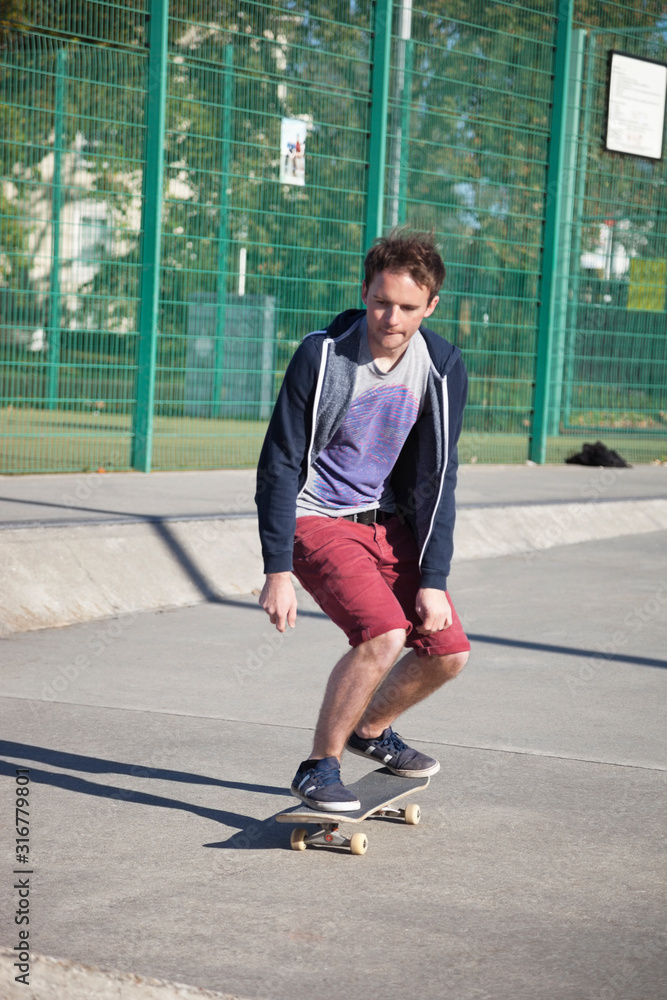 Fototapeta premium Young man skateboarding on road