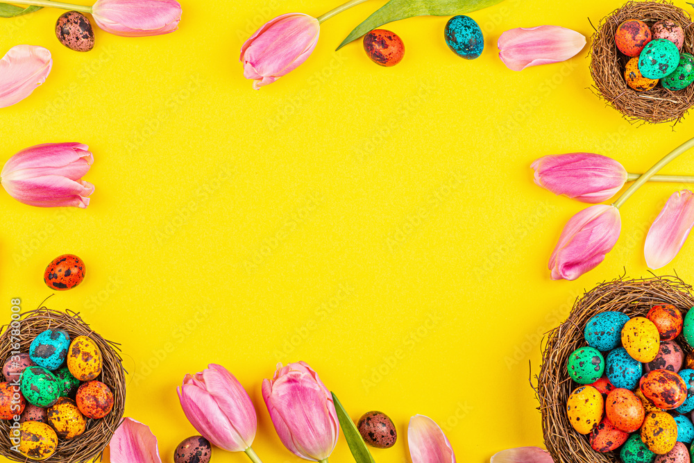 Stylish background with colorful easter eggs isolated on yellow background with pink tulip flowers. Flat lay, top view, mockup, overhead, template