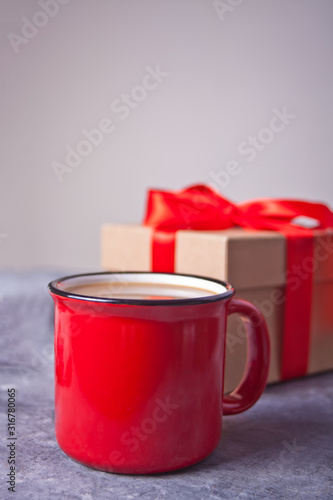 Red mug of coffee, gift box on the gray table