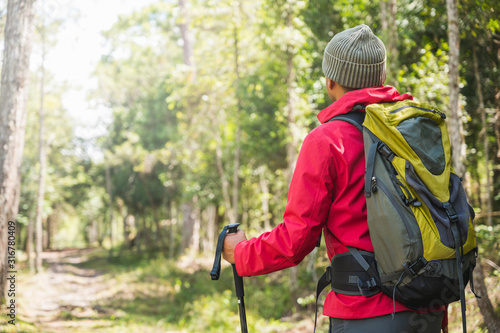 Hipster Hikers wear red raincoats, green backpacks, travel into the deep forest. © Nopphon
