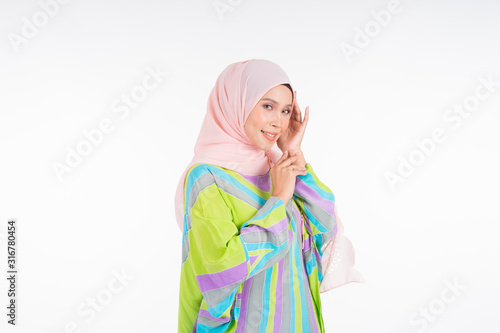 Beautiful female model wearing a pastel batik kaftan/caftan, a traditional dress for Muslim women isolated over white background. Stylish Muslim female hijab fashion lifestyle portraiture concept.