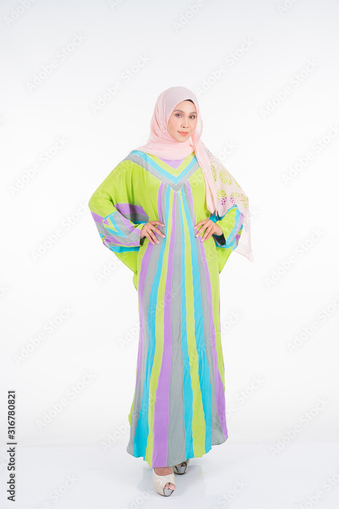Beautiful female model wearing a pastel batik kaftan/caftan, a traditional dress for Muslim women isolated over white background. Stylish Muslim female hijab fashion lifestyle portraiture concept.