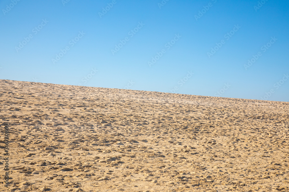 Blue sky over a golden yellow sand dune with a lot of structures and shapes close to a beach where pople enjoy a sunbath and their holiday vacation travel Blue sky over a golden yellow sand dune with a lot of structures and shapes close to a beach where pople enjoy a sunbath and their holiday vacation travel