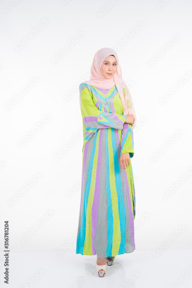 Beautiful female model wearing a pastel batik kaftan/caftan, a traditional dress for Muslim women isolated over white background. Stylish Muslim female hijab fashion lifestyle portraiture concept.