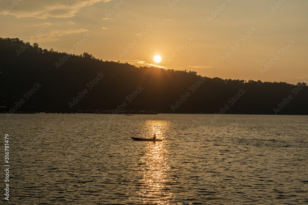 Traveller canoeing on a calm lake during sunset