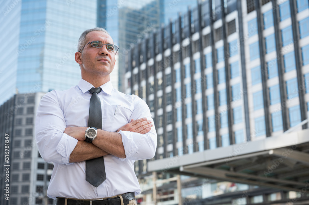 Portrait of senior businessman doing thinking,smiling,arm cross on building business background Portrait of senior businessman doing thinking,smiling,arm cross on building business background