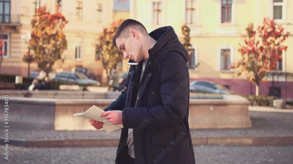 Handsome guy comes in focus. He lost in foreign city. Confused facial expression. Tourist is asking for help, talking on the phone. Copy space. Action. Animation. 4K. Handsome guy comes in focus. He lost in foreign city. Confused facial expression. Tourist is asking for help, talking on the phone. Copy space. Action. Animation. 4K.