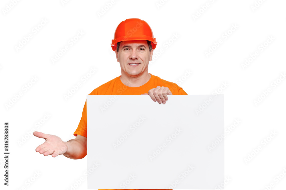 White smiling middle-aged handsome worker wearing orange hard hat, holding blank paper sheet in hand White smiling middle-aged handsome worker wearing orange hard hat, holding blank paper sheet in hand