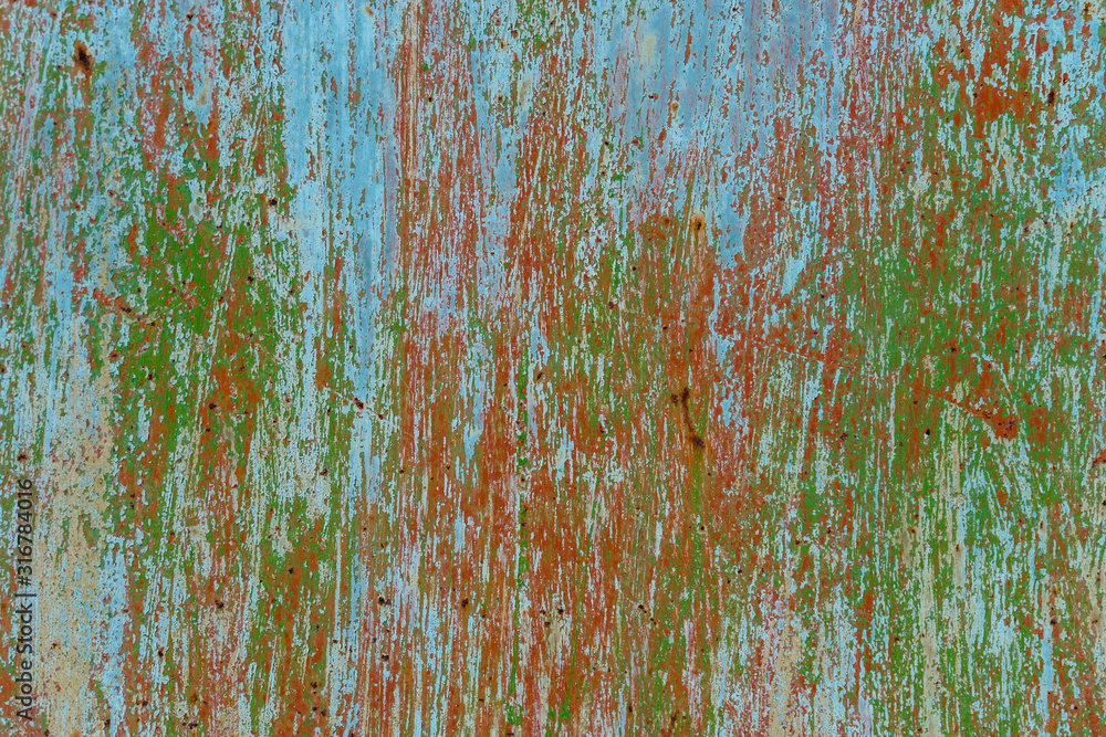 Old painted scratched streaked metal surface. Several layers of paint are visible: brown, green, blue. Abstract colorful texture background Old painted scratched streaked metal surface. Several layers of paint are visible: brown, green, blue. Abstract colorful texture background