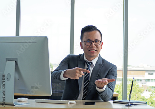  young asian businessman sitting in office and pointing something on the hand