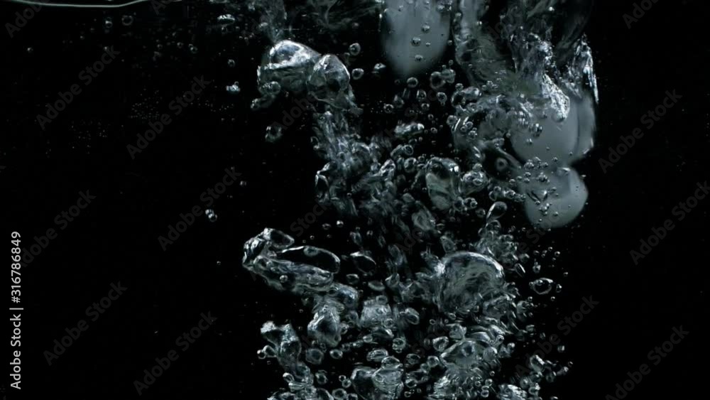 Slow motion ice cubes falling down in water on black background with splash, bubbles and drops Slow motion ice cubes falling down in water on black background with splash, bubbles and drops