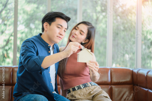 Portrait Of Happy Couple Inserting Coin In Homebank photo