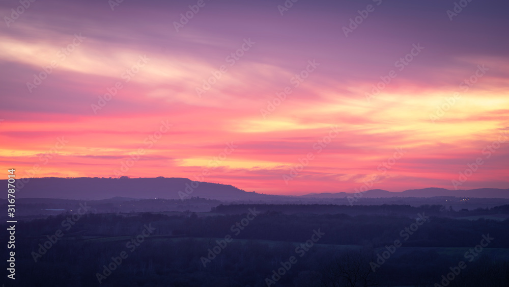 A colourful winter sunset over the Avon valley with the Cotswold escarpment in the distance.