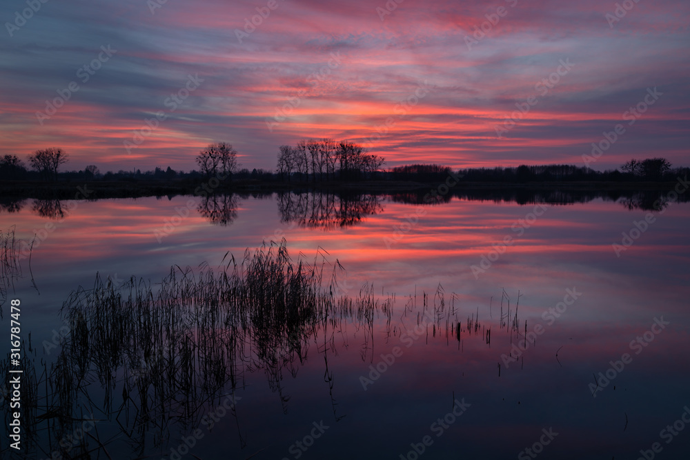 The reflection of colorful clouds in the water after sunset in Stankow, Poland