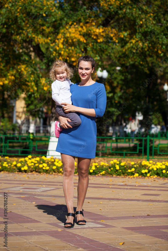 Obraz premium Closeup portrait of a young beautiful mother with little curly daughter in autumn park