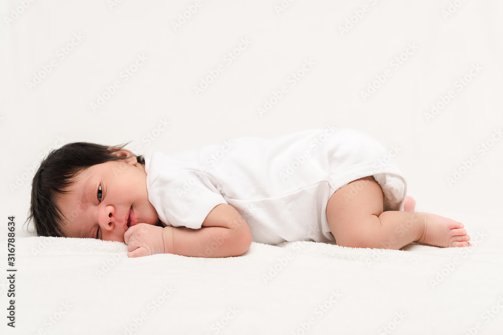 adorable bi-racial newborn in baby romper lying isolated on white adorable bi-racial newborn in baby romper lying isolated on white