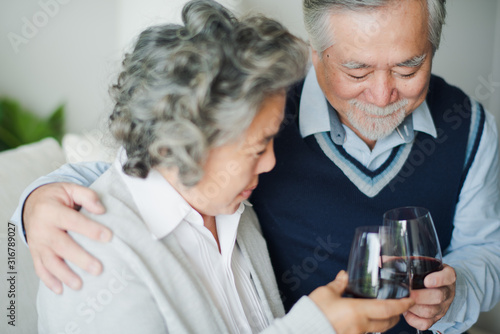 Senior Asian couple love celebration birthday, Retired man and woman drinking wine and champagne in living room at home which smiling and felling happy. Celebration birthday concept