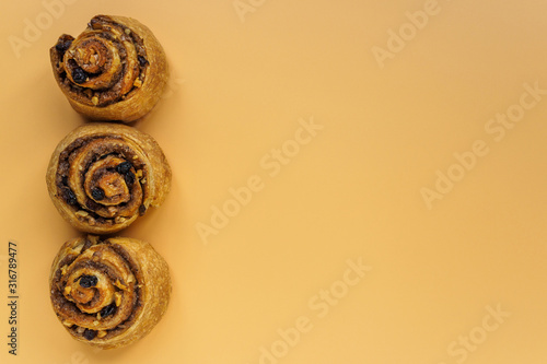 Cinnamon, nut and raisin buns on orange background with copy space
