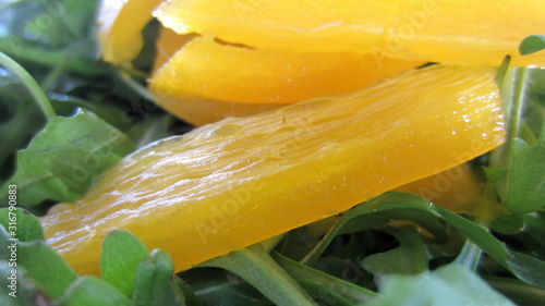 A close-up of pieces of yellow pepper cut into strips on a rocket salad. 
