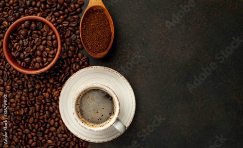 Cup of tasty coffee and beans on a stone background. Top view with copy space for your text.