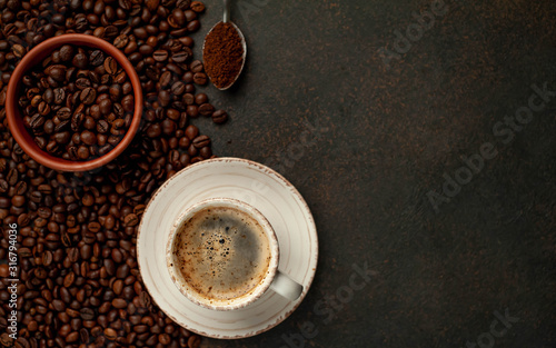 Cup of tasty coffee and beans on a stone background. Top view with copy space for your text.