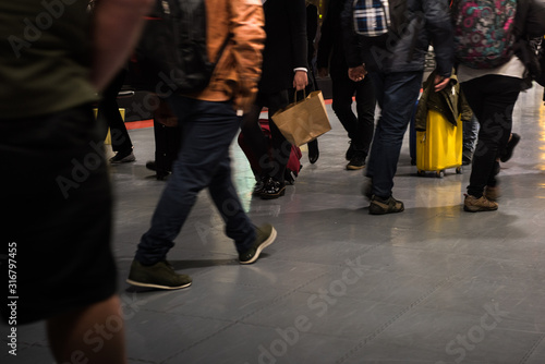 Detail of the legs of many tourists walking through the airport terminal