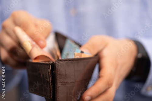 Hands opening a leather wallet with Euro banknotes inside