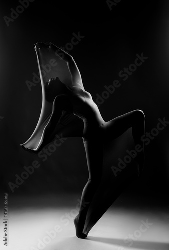 Slim girl wearing a white bodysuit dances a modern avant garde dance, covering her body with elastic transparent fabric. Artistic, conceptual, monochrome and creative design. Silhouette photography.