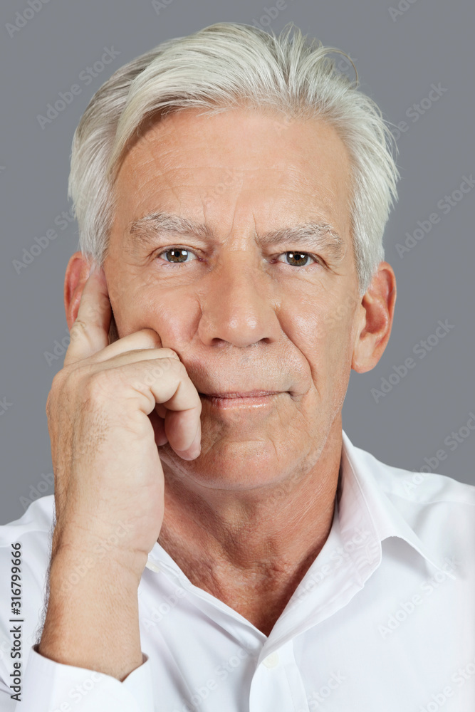 Close-up portrait of senior man thinking over gray background Close-up portrait of senior man thinking over gray background