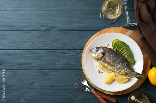 Bilde på lerret Plate with baked Dorado fish on garnished wooden background, top view