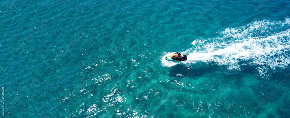 Aerial drone ultra wide photo of jet ski couple cruising in high speed in tropical exotic bay with emerald sea