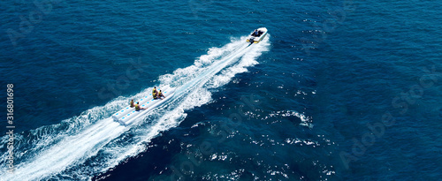 Aerial drone ultra wide photo of extreme powerboat donut water-sports cruising in high speed in tropical turquoise bay