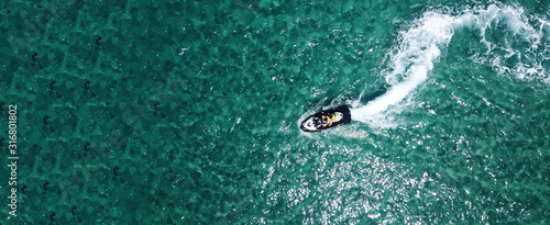 Aerial drone ultra wide photo of jet ski couple cruising in high speed in tropical exotic bay with emerald sea © aerial-drone