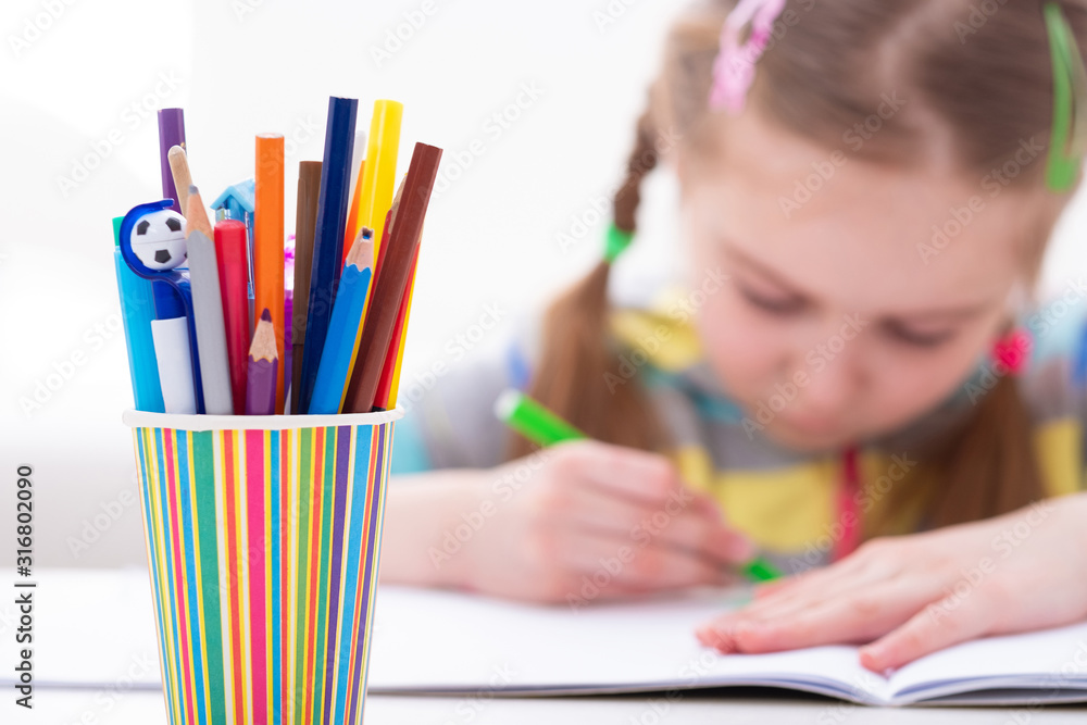 Adorable young female pupil carefully working in her copybook, on white background Adorable young female pupil carefully working in her copybook, on white background