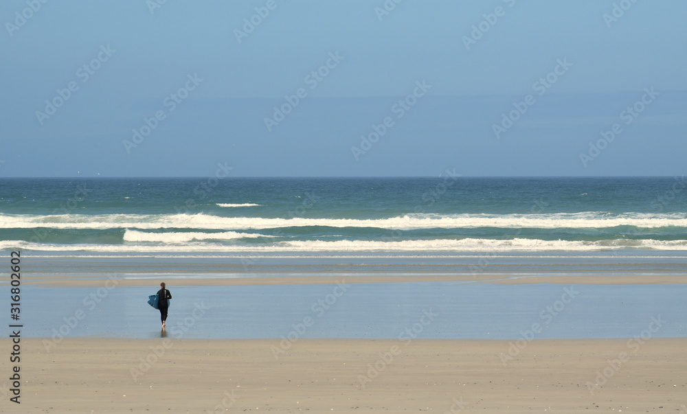 Dans la baie d'Audierne dans le Finistère en Bretagne un surfeur s'apprête à affronter les vagues et à glisser sur leurs crêtes