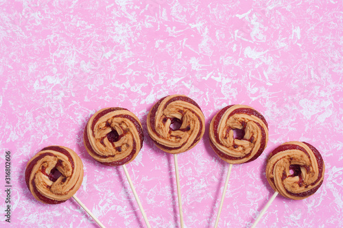 Shortbread cookies with berry jam in the form of lollipops on a pink background
