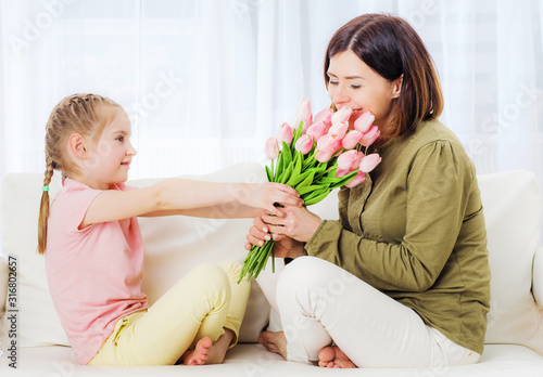 Loving kid giving bouquet of flowers to congratulate on Mothers day