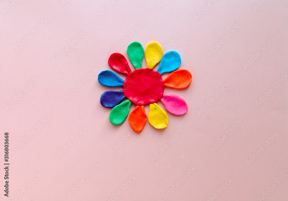 cute flower made of multi-colored plasticine clay on a pink background, multi-colored dough, minimal, children's crafts