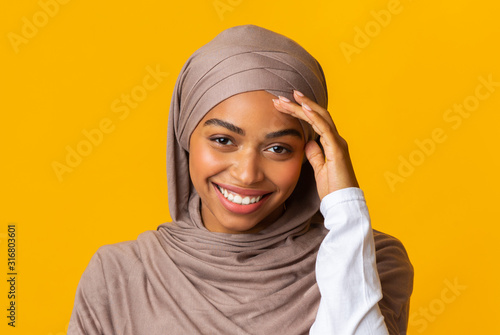 Tablou pe pânză Smiling afro muslim girl in headscarf shyly looking at camera