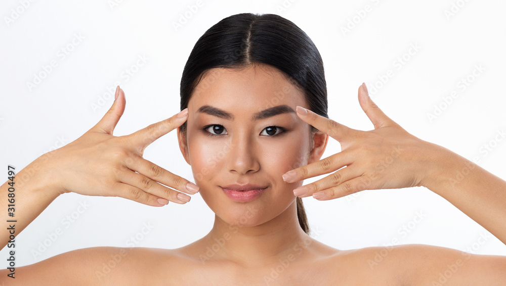 Young asian girl holding fingers near eyes and looking at camera Young asian girl holding fingers near eyes and looking at camera