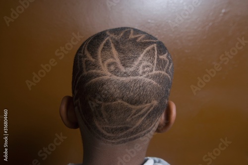 The back of a young boys head with shaven art work in his hair