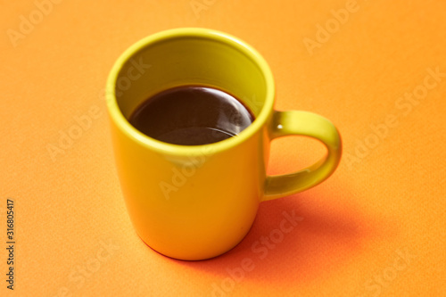 green cup with coffee on an orange background.