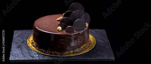 Fancy mirror glaze chocolate cake on dark background